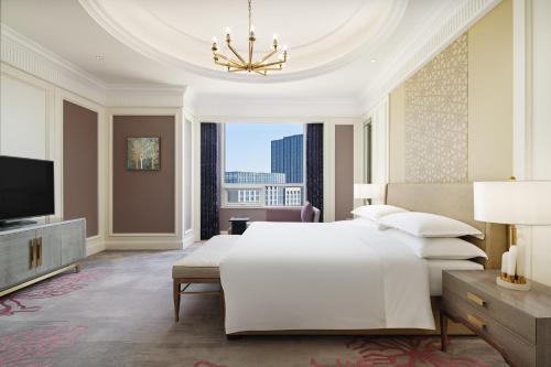 a bedroom with a large white bed and a tv at Sheraton Yinchuan in Yinchuan