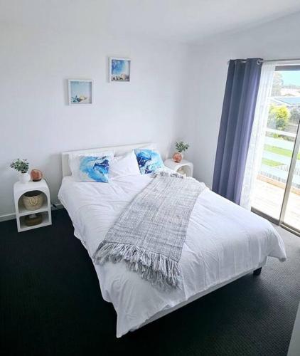 białe łóżko w sypialni z oknem w obiekcie San Remo Coastal Apartment w mieście San Remo