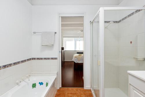 a white bathroom with a tub and a shower at Rosebud Hideaway - Cute Contemporary by the Beach in Rosebud