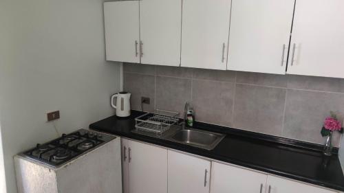 a kitchen with white cabinets and a sink and a stove at Departamento Reñaca Quinto Sector en calle Bellavista in Viña del Mar