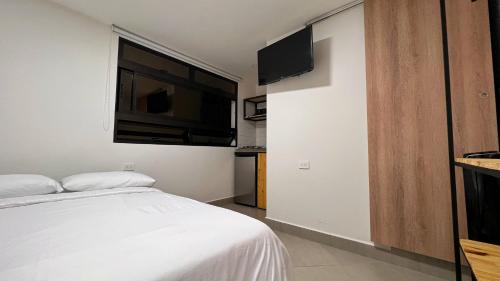 Un dormitorio con una cama y un televisor de pantalla plana. en Casa hotel Los Laureles, en Medellín