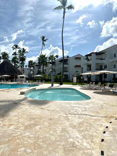a resort swimming pool with chairs and palm trees at Fully renovated Beachfront 1BR Condo in the gated Stanza Mare community with a private beach, pool, onsite restaurant and modern amenities such as refrigerator, dishwasher, filtered water, microwave, BBQ, washer dryer, bamboo linens, free Wi-Fi in Punta Cana