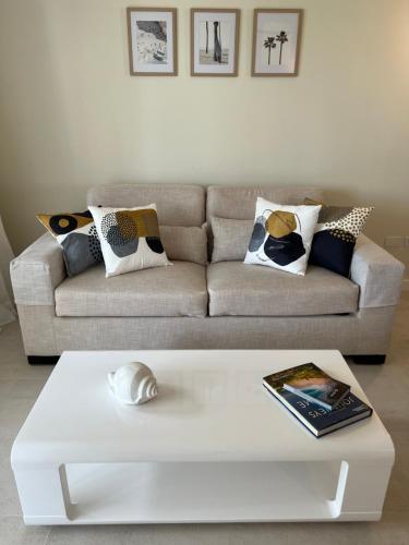 a living room with a couch and a white coffee table at Fully renovated Beachfront 1BR Condo in the gated Stanza Mare community with a private beach, pool, onsite restaurant and modern amenities such as refrigerator, dishwasher, filtered water, microwave, BBQ, washer dryer, bamboo linens, free Wi-Fi in Punta Cana