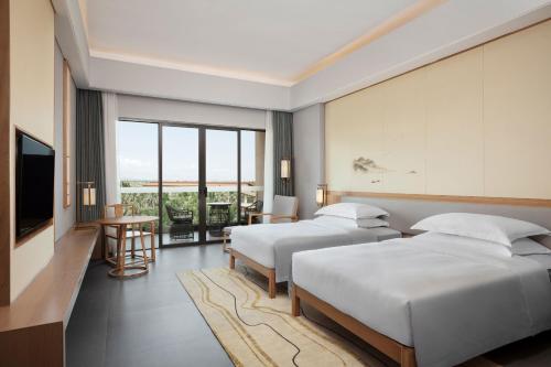 a hotel room with two beds and a television at Sheraton Maoming Romantic Beach Resort in Maoming