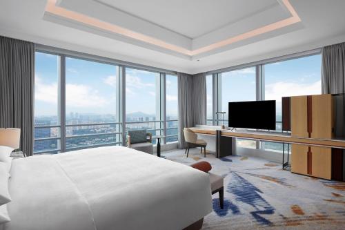 um quarto de hotel com uma cama, uma secretária e janelas em Sheraton Guangzhou Panyu em Guangzhou