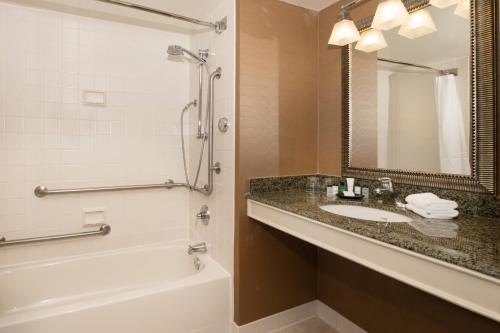 W łazience znajduje się umywalka, wanna i lustro. w obiekcie Sheraton Hartford South w mieście Rocky Hill
