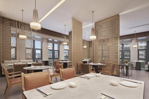 a restaurant with tables and chairs and windows at Four Points by Sheraton Guiyang, Huaxi in Guiyang