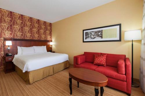 a hotel room with a bed and a red couch at Courtyard by Marriott Chicago Schaumburg/Woodfield Mall in Schaumburg