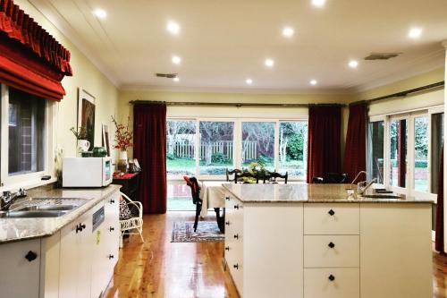 une cuisine avec des placards blancs et une grande fenêtre dans l'établissement Hope View Retreat, à Bathurst
