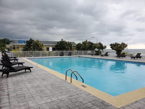 a large swimming pool with chairs and the ocean in the background at serendipity on the beach Ocho Rios in Saint Annʼs Bay