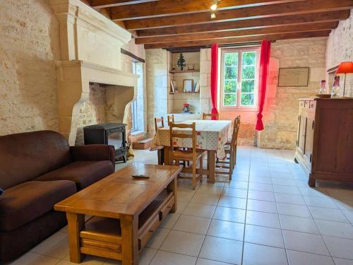 un salon avec un canapé et une table dans l'établissement Maison de charme en pierres, avec terrasse, jardin, vélos, poêle à bois et borne de recharge électrique - FR-1-653-79, à Asnières-sur-Nouère