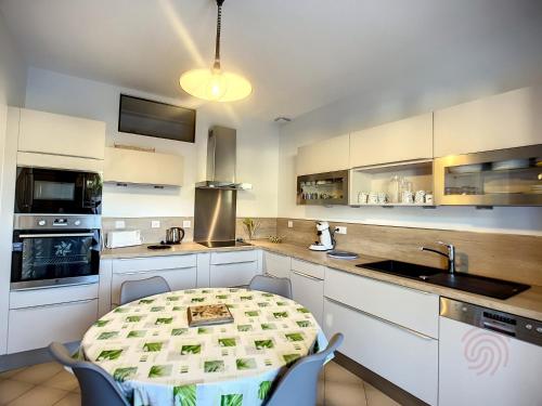 une cuisine avec des armoires blanches et une table avec des chaises dans l'établissement Maison F4 avec terrasse, parking et animaux acceptés - FR-1-451-185, à Lamalou-les-Bains