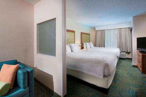 a hotel room with two beds and a blue couch at SpringHill Suites by Marriott Atlanta Alpharetta in Alpharetta