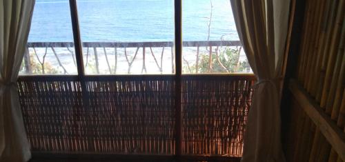 a window with a view of the ocean from a beach at Pombero lodge in Tano