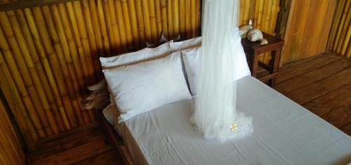 1 dormitorio con 1 cama con sábanas y almohadas blancas en Pombero lodge en Tano