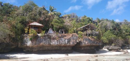um grupo de cabanas numa rocha numa praia em Pombero lodge em Tano