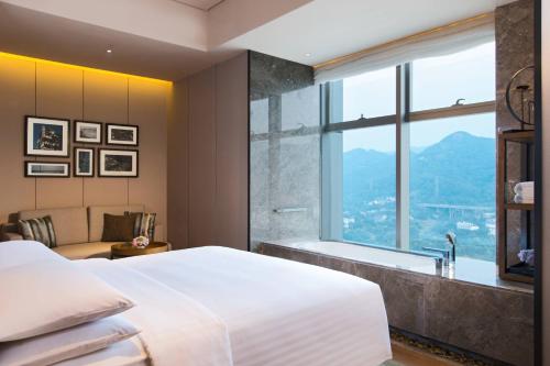 a bedroom with a bed and a tub and a window at Chongqing Marriott Hotel in Chongqing