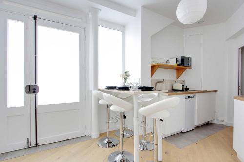 una cocina blanca con encimera y taburetes en Superbe duplex à proximité du Sacré Coeur!, en París