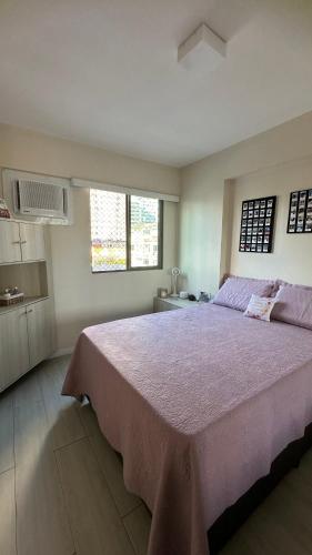 レシフェにあるApartamento no Rosarinhoの紫色の毛布が掛けられた大きなベッドのある寝室