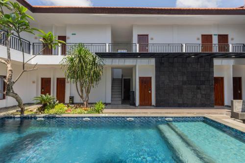 a villa with a swimming pool in front of a house at The Baliem Hotel in Jimbaran