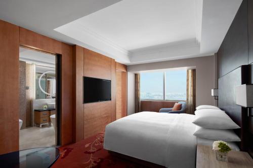 蘇州市にあるスジョウ マリオット ホテルの大型ベッドとテレビが備わるホテルルームです。