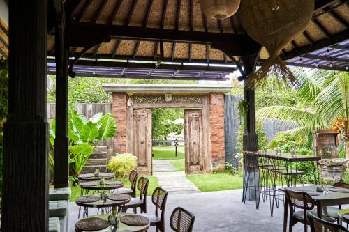 an outdoor patio with tables and chairs and a doorway at ONAYA Bali Resort - Adults Only in Uluwatu