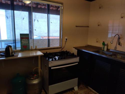 a kitchen with a stove top oven next to a sink at Geriba surfing in Búzios