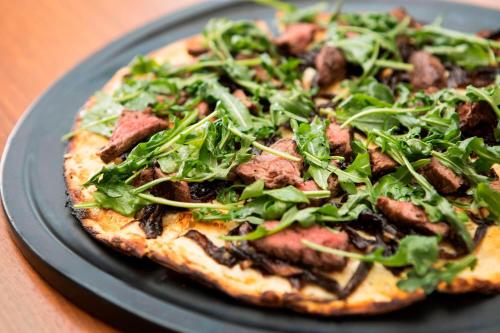 a pizza with greens on a black plate on a table at San Francisco Airport Marriott Waterfront in Burlingame