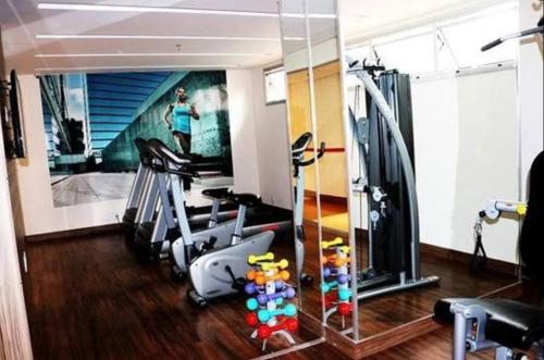 a gym with tread machines and a painting of a woman at 511. Flat Hotel S4 in Brasilia