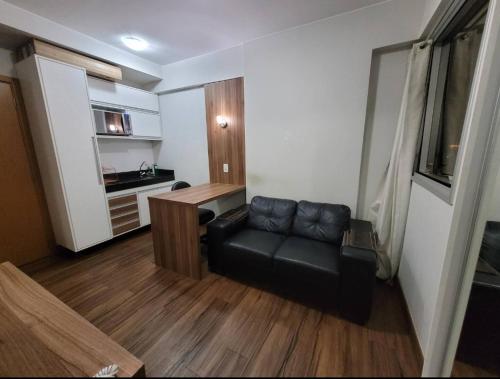 a living room with a black leather couch and a kitchen at 511. Flat Hotel S4 in Brasilia