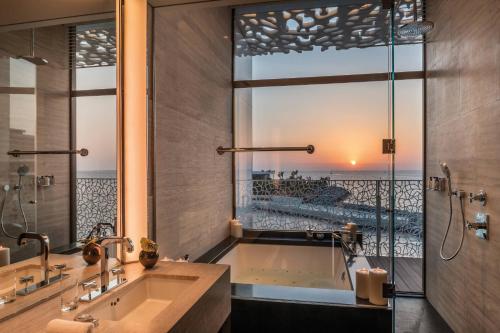 a bathroom with a tub and a large window at Bulgari Resort, Dubai in Dubai