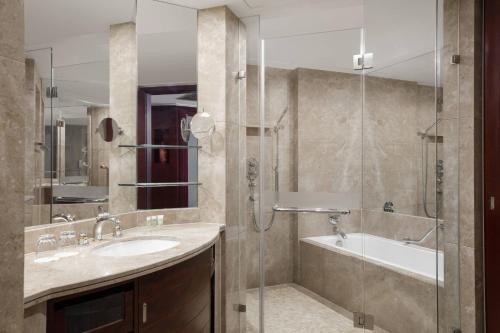 a bathroom with a tub and a sink and a shower at Courtyard by Marriott Shanghai Fengxian in Fengxian