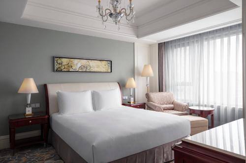 a hotel room with a bed and a chair at Courtyard by Marriott Shanghai Fengxian in Fengxian