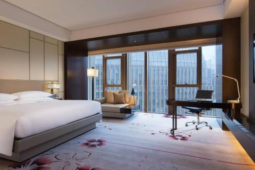 a bedroom with a bed and a desk and a piano at Renaissance Nanjing Olympic Centre Hotel in Nanjing