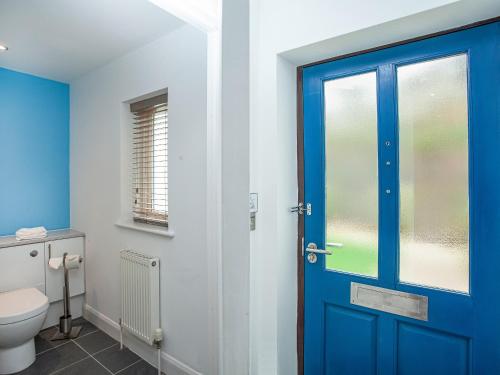 a bathroom with a blue door and a toilet at Villa Gallery-77 in Perranwell