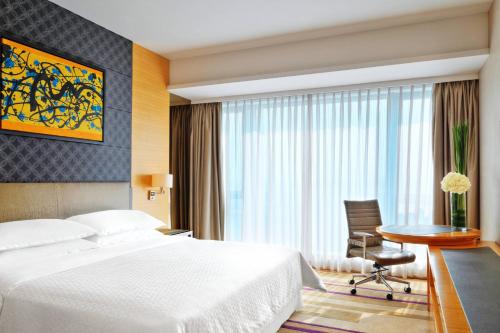 広州市にあるFour Points by Sheraton Guangzhou, Dongpuのベッド、椅子、テーブルが備わるホテルルームです。