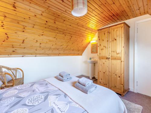 een slaapkamer met een bed en een houten plafond bij Bunloit Farmhouse - Uk45397 in Lewiston