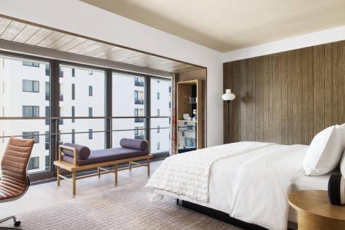 a bedroom with a bed and a chair and a large window at Le Meridien Shenyang Heping in Shenyang