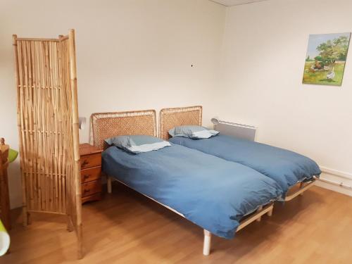 een slaapkamer met een bed met blauwe lakens en een dressoir bij Gîte Bucy-Saint-Liphard, 1 pièce, 2 personnes - FR-1-590-402 