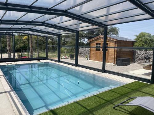 - une piscine avec un toit en métal dans l'établissement Gîte rénové avec piscine couverte chauffée, spa, climatisation et équipements PMR à Couzon - FR-1-489-483, à Couzon