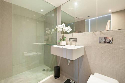 a white bathroom with a sink and a shower at DH707 - 1 bedroom unit Victoria St - Darlinghurst in Sydney
