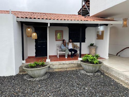 two women sitting on the porch of a house at Aguas Claras Luxury Hospedaje in Filandia