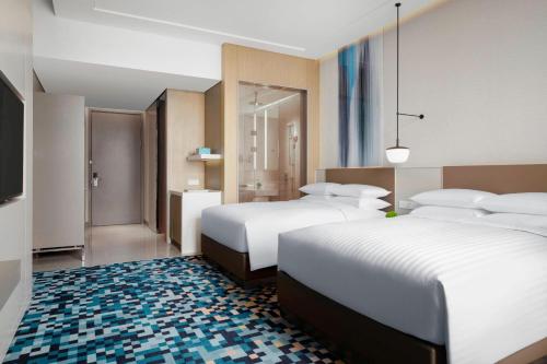 a hotel room with two beds and a television at Courtyard by Marriott Shanghai Minhang in Shanghai