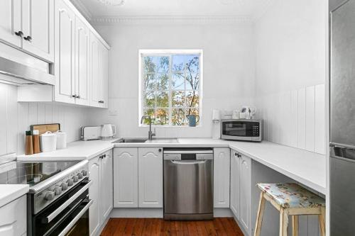 a white kitchen with white cabinets and a window at Harriette St Hideaway 2-Bed Apt in Neutral Bay HAR10 in Sydney