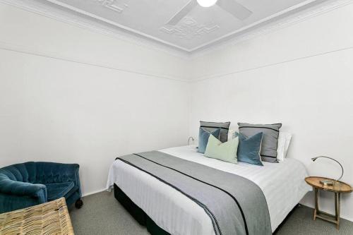 a white bedroom with a bed and a blue chair at Harriette St Hideaway 2-Bed Apt in Neutral Bay HAR10 in Sydney