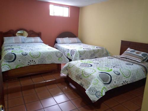 um quarto com 2 camas e uma janela em Hostal Locuras en el Cielo em Baños