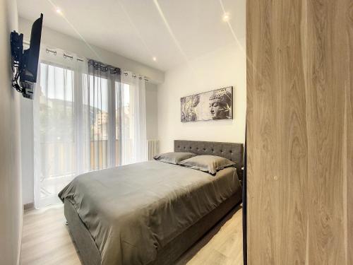 a bedroom with a bed and a large window at Escapades Ensoleillées in Nice