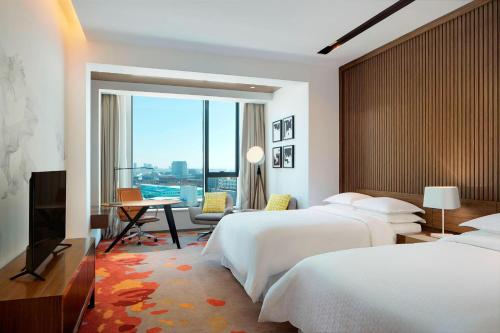 Habitación de hotel con 2 camas y escritorio en Four Points by Sheraton Changchun Hi-Tech Zone, en Changchún