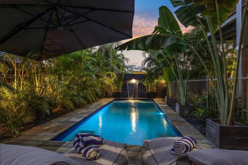 uma piscina num quintal com plantas e um guarda-sol em Lush Tropical Paradise Home - Darwin City em Stuart Park
