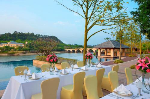 a table with white table cloths and chairs next to a river at Sheraton Bailuhu Resort, Huizhou in Huizhou